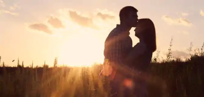 Casal de Namorados se abraçando e curtindo seu Amor com o Sol ao fundo.
